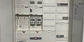 Der Verteilerkasten zeigt verschiedene elektrische Komponenten, darunter Zähler und Sicherungen, in einem modernen Design.