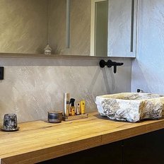 Ein elegantes Badezimmer mit einem Holzwaschtisch, einem Steinwaschbecken und stilvollen Accessoires auf der Ablage.