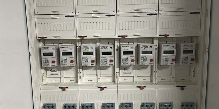 Eine Wand mit mehreren Stromzählern, die ordentlich in einem weißen Gehäuse angeordnet sind, zeigt die Verbrauchswerte an.