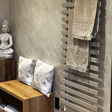Der Raum zeigt eine harmonische Kombination aus Holz und sanften Farben, ergänzt durch eine Buddha-Statue und frische Blumen.