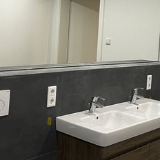 Das Badezimmer zeigt ein stilvolles Doppelwaschbecken mit klaren Linien und einem großen Spiegel über der Ablage.